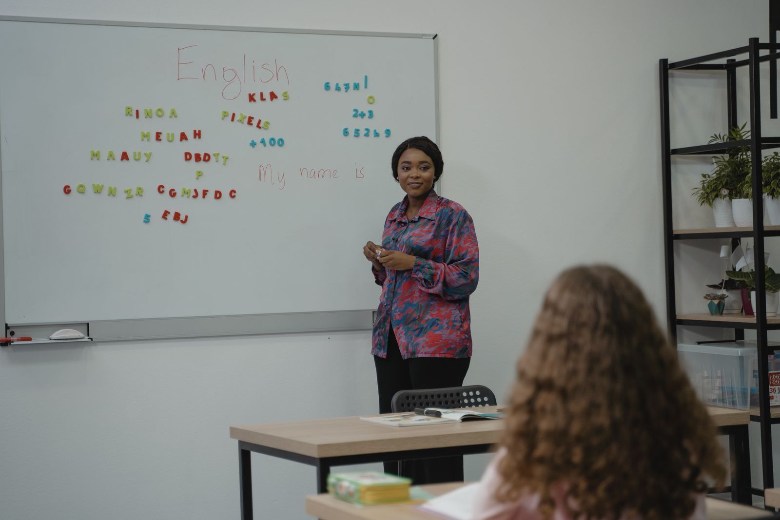 A teacher standing at a whiteboard with the word English written on it during an ESL lesson