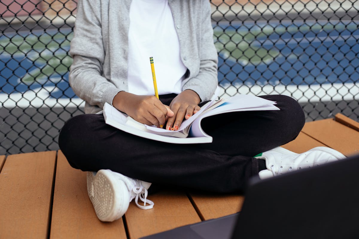 A school-aged child writing notes in a copybook at a desk