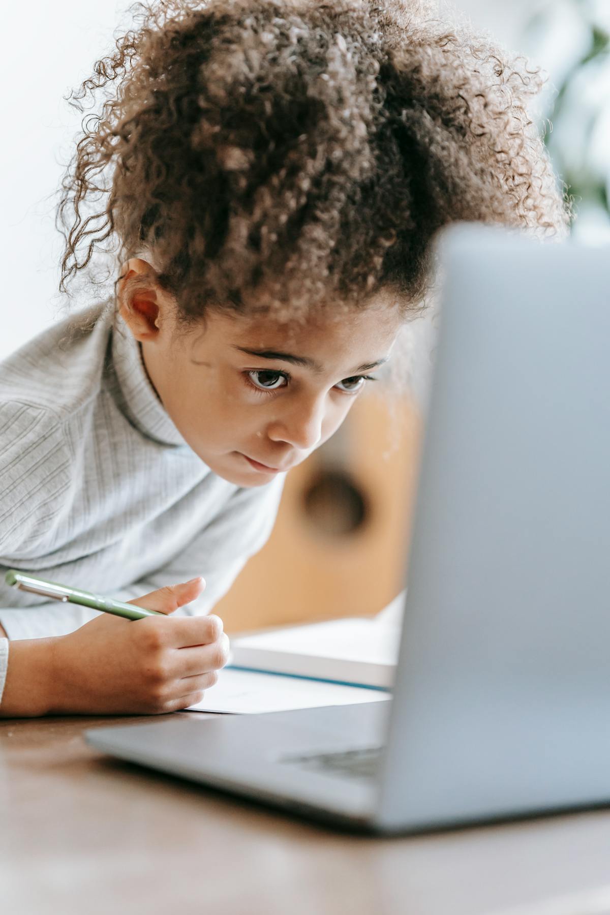 A child practicing typing on a laptop at a desk at home