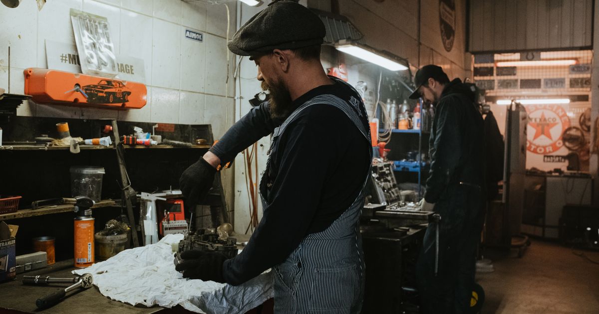 Two mechanics working on parts at a bench in an auto repair shop, the kind of skilled trade a certification leads into
