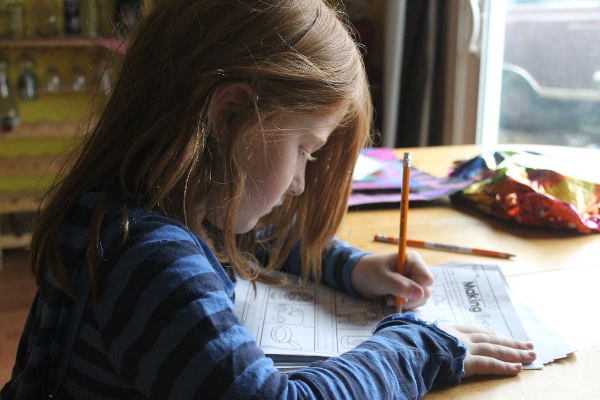 Child practicing handwriting with a pencil at a desk